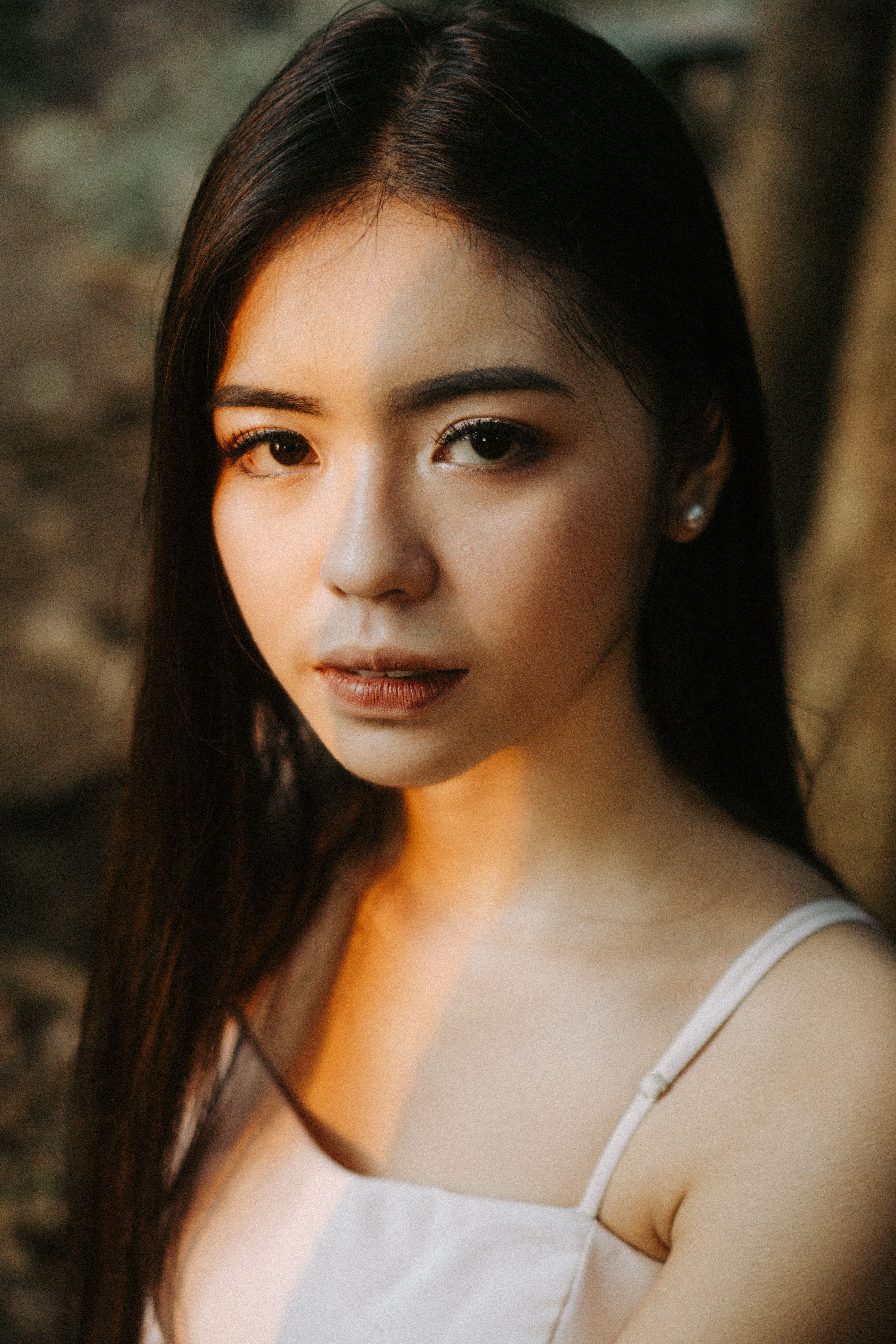 Close-up portrait of a young woman with long hair, captured outdoors in natural light.