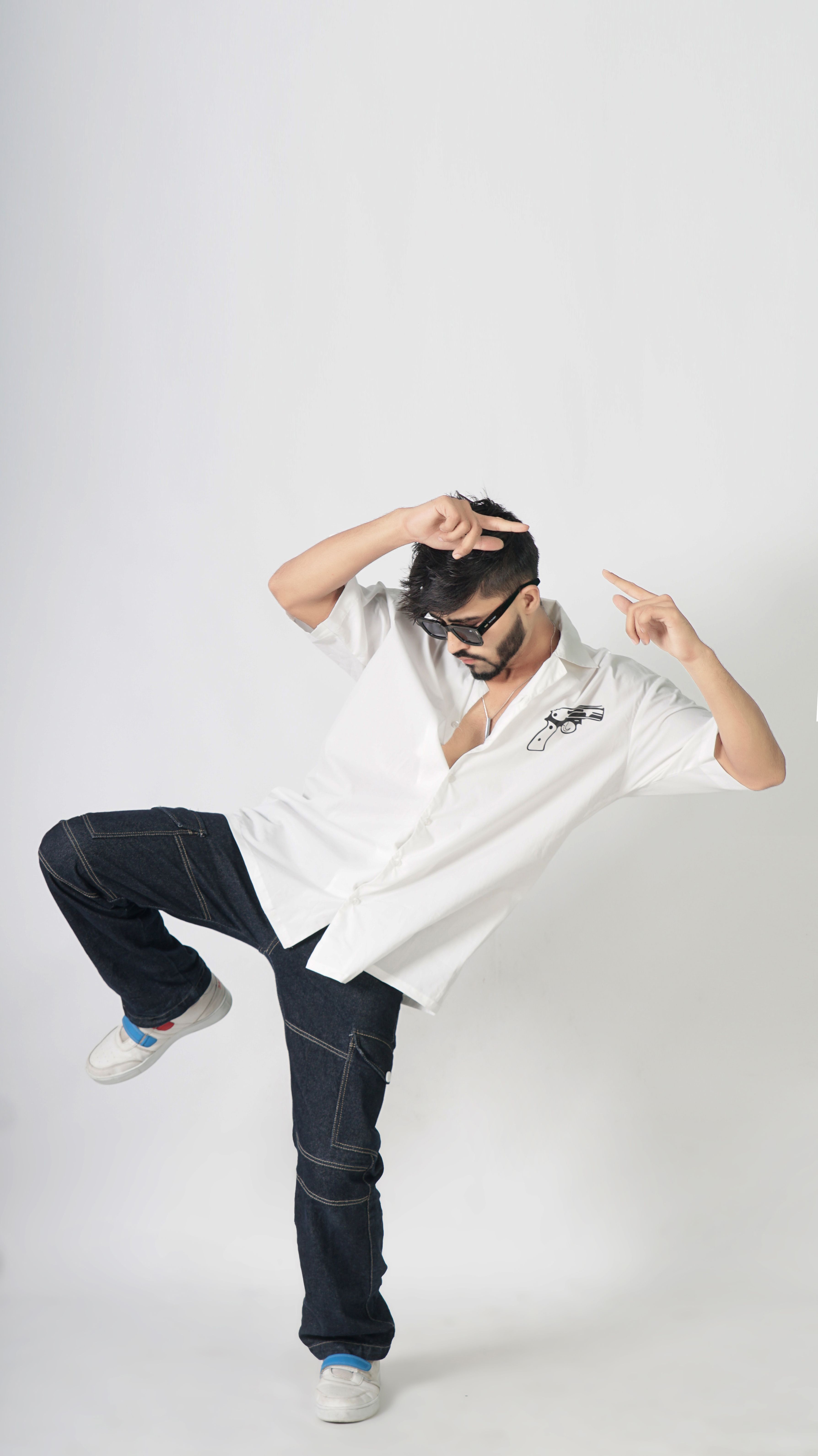 Man in casual outfit striking a dynamic pose in a studio setting, showcasing modern fashion.