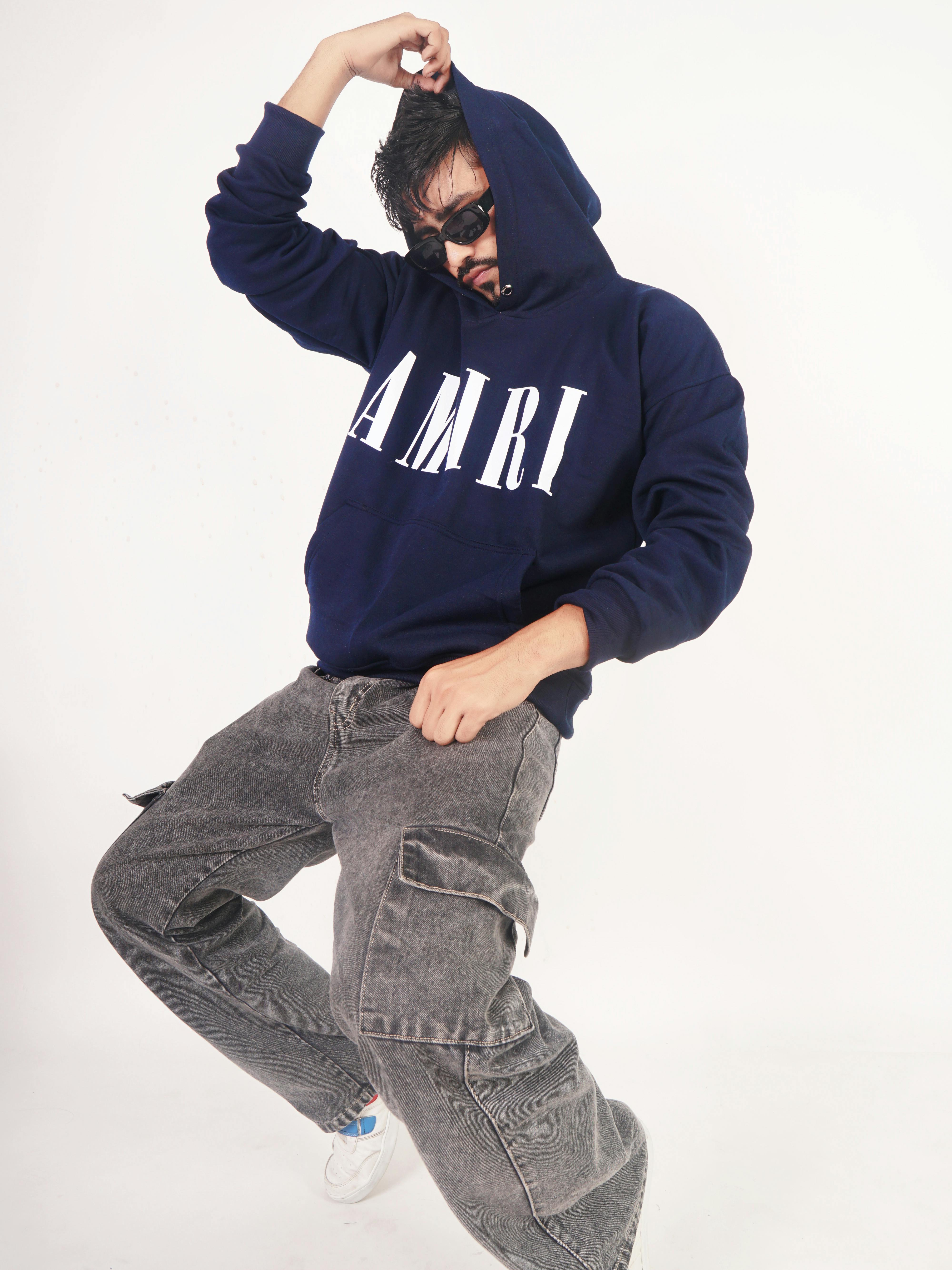 Model in a Navy Blue Hoodie with the AMIRI Print and Faded Black Jeans Free Stock Photo