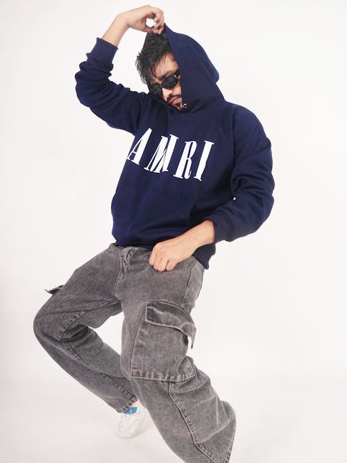 Model in a Navy Blue Hoodie with the AMIRI Print and Faded Black Jeans