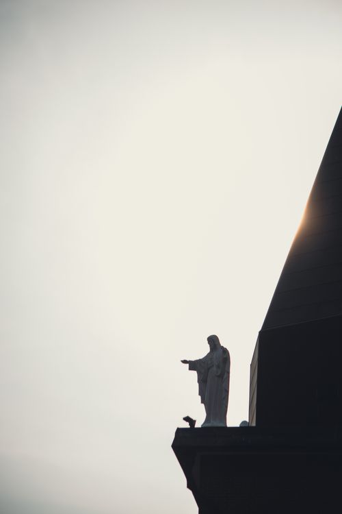 Free Silhouette of a religious statue against a bright sun, capturing a serene and spiritual ambiance. Stock Photo
