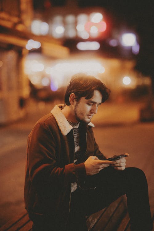 Man Sitting with Smartphone at Night 