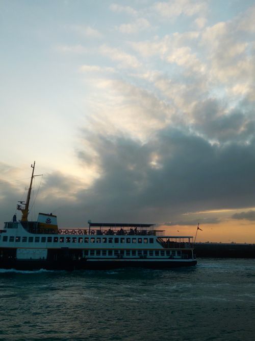 Free A picturesque ferry cruising at sunset, casting serene reflections on tranquil waters. Stock Photo