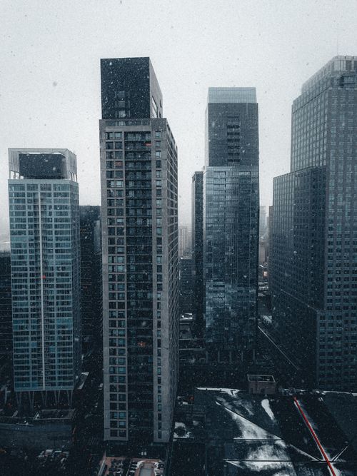 Free A striking cityscape featuring modern skyscrapers amidst snowfall, creating an urban winter scene. Stock Photo