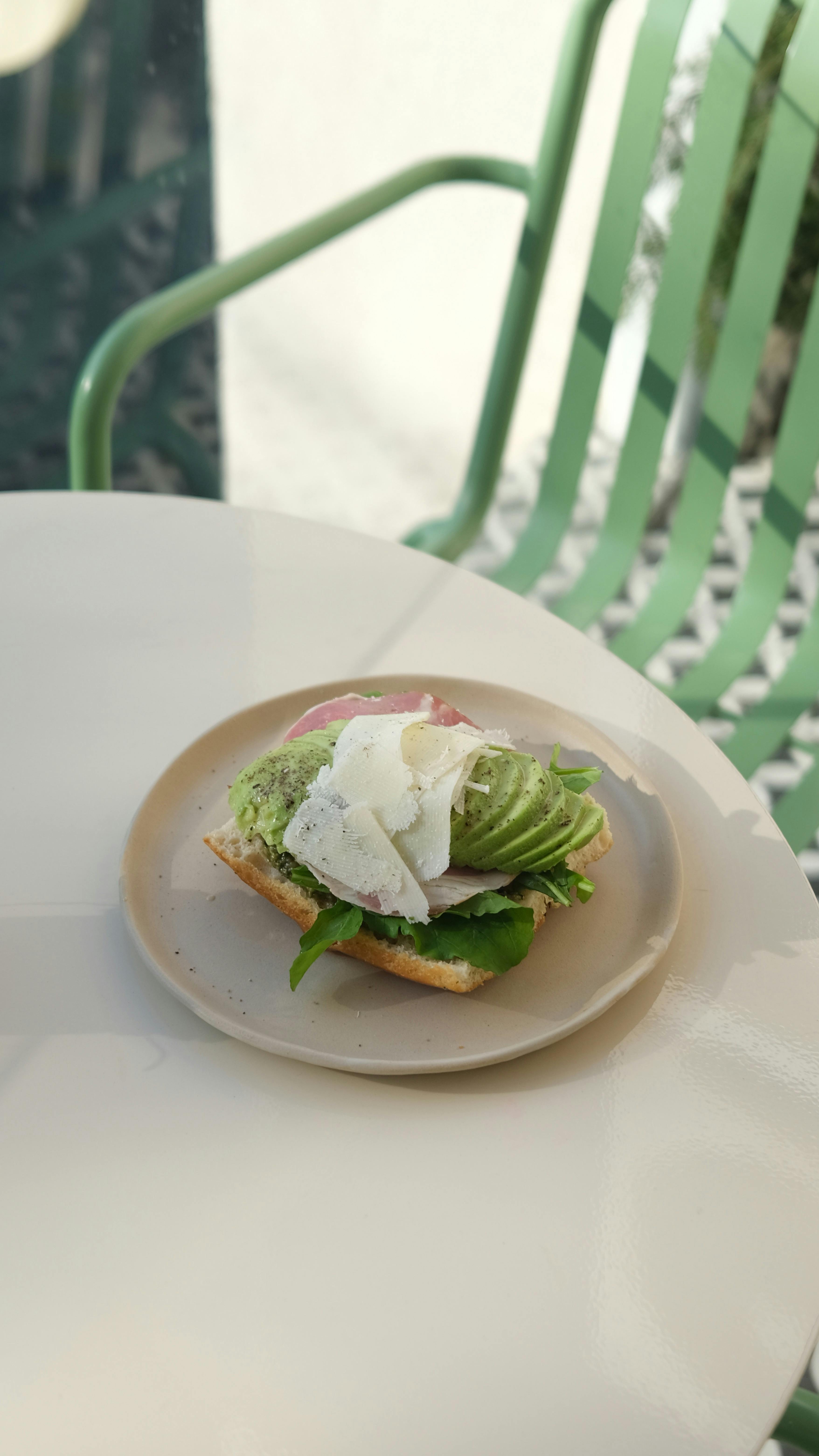 Close-up of gourmet avocado toast with cheese on a sunlit table.