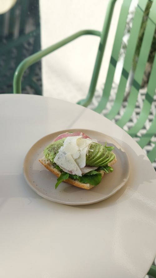 Free Close-up of gourmet avocado toast with cheese on a sunlit table. Stock Photo