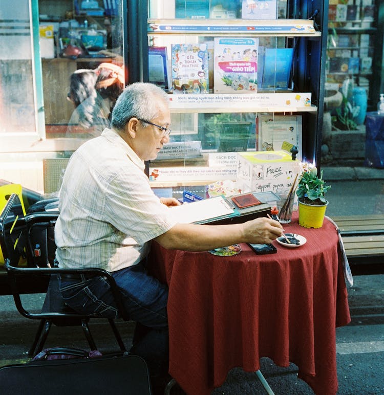 Man Sitting At Cafe And Drawing