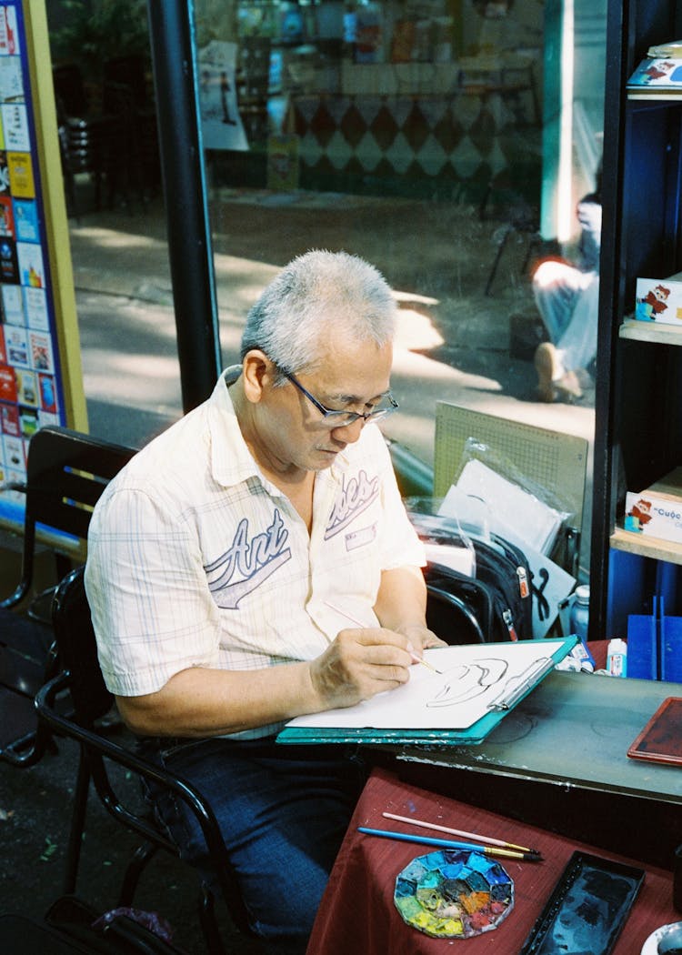 Man Sitting On Chair And Drawing