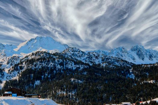 Majestic snowy mountains under dramatic clouds in Canillo, Andorra.