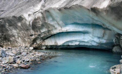 Free Explore the serene beauty of a glacier ice cave with a tranquil turquoise pool formed by melting snow and ice. Stock Photo