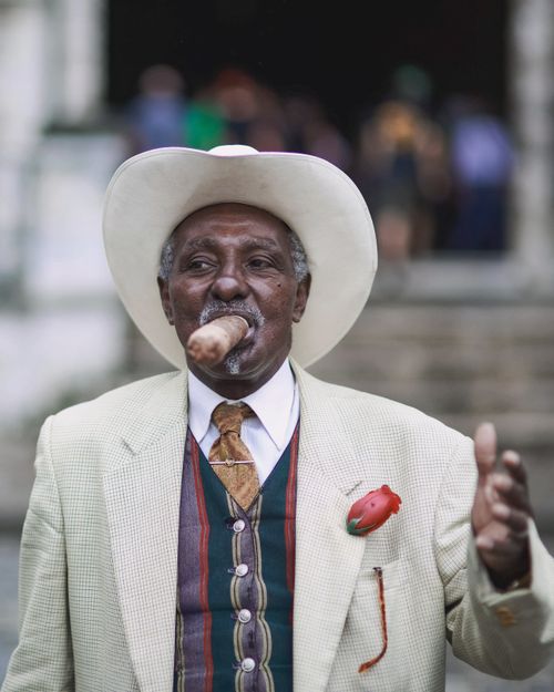 Free Stylish senior man in suit and hat smoking a cigar, embodies sophistication. Stock Photo