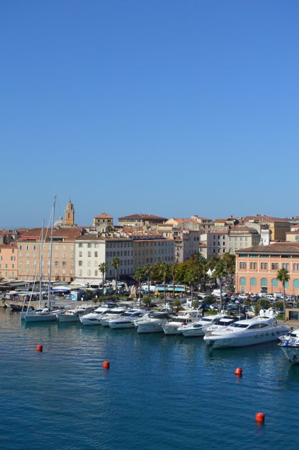 Beautiful sunny day at a Mediterranean harbor with boats and historic architecture.