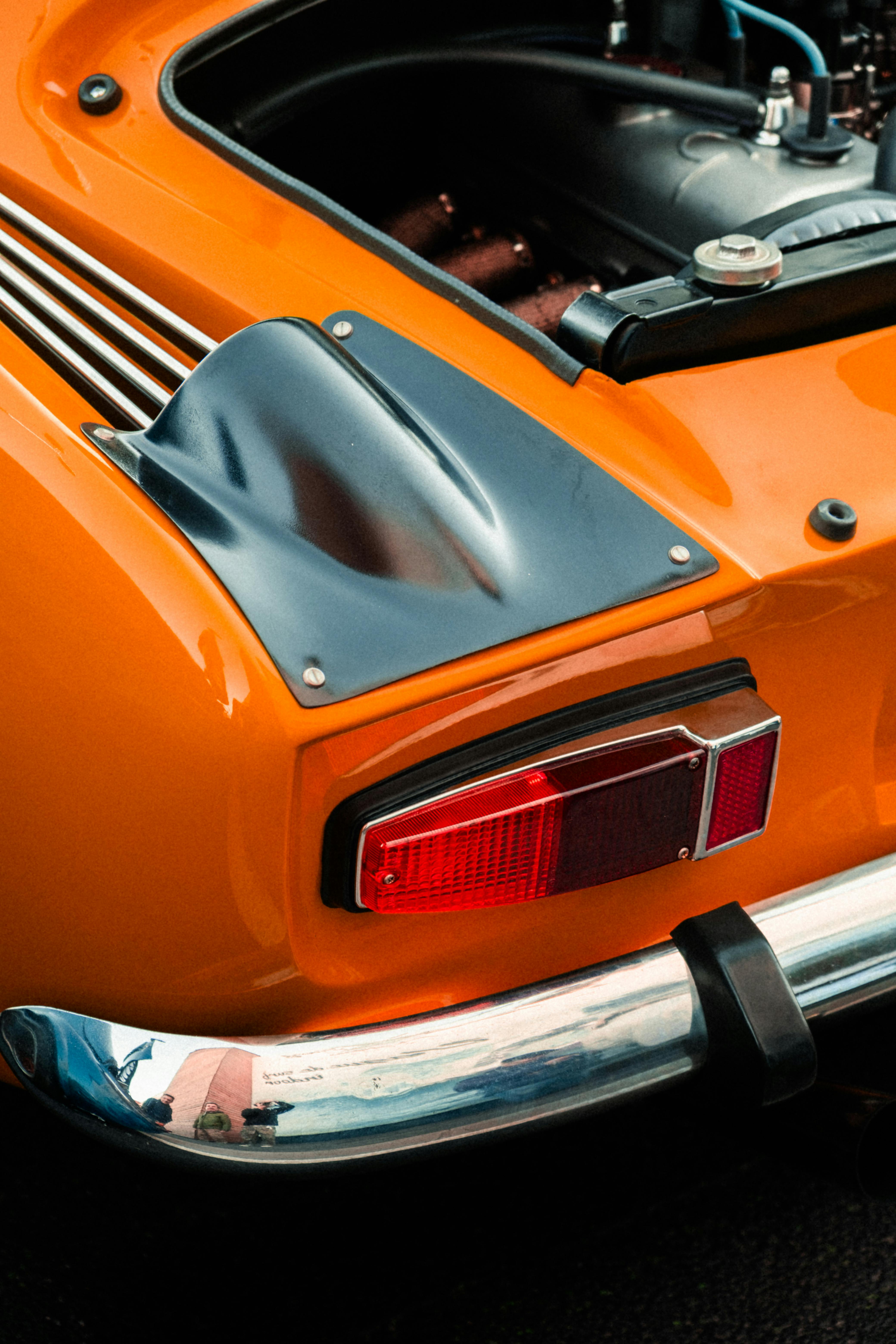 Close-up of a retro sports car's rear with vibrant orange color and chrome details.