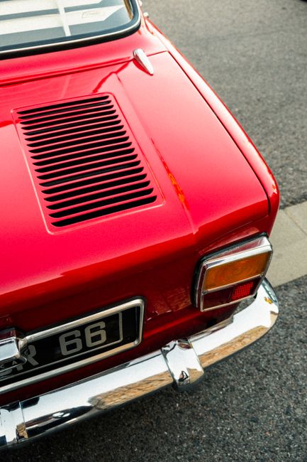 Detailed shot of a classic red vintage car's tail light on asphalt.