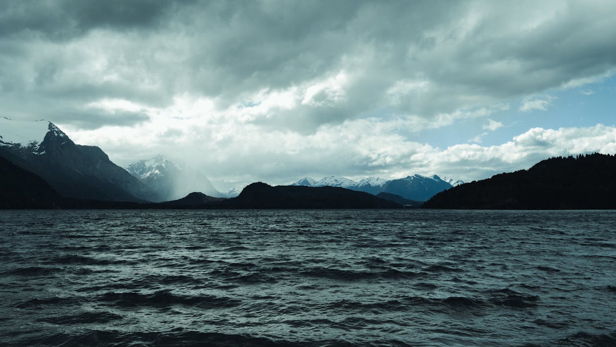 View of a Body of Water and Snowcapped Mountains under a Cloudy Sky 