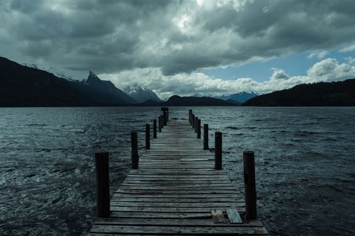 Free A wooden pier extends into a scenic lake surrounded by mountains in San Carlos de Bariloche, Argentina. Stock Photo