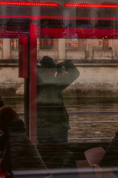 A man taking pictures through a window with urban reflections and red accents.