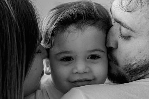 Parents Kissing Their Baby on the Cheeks 