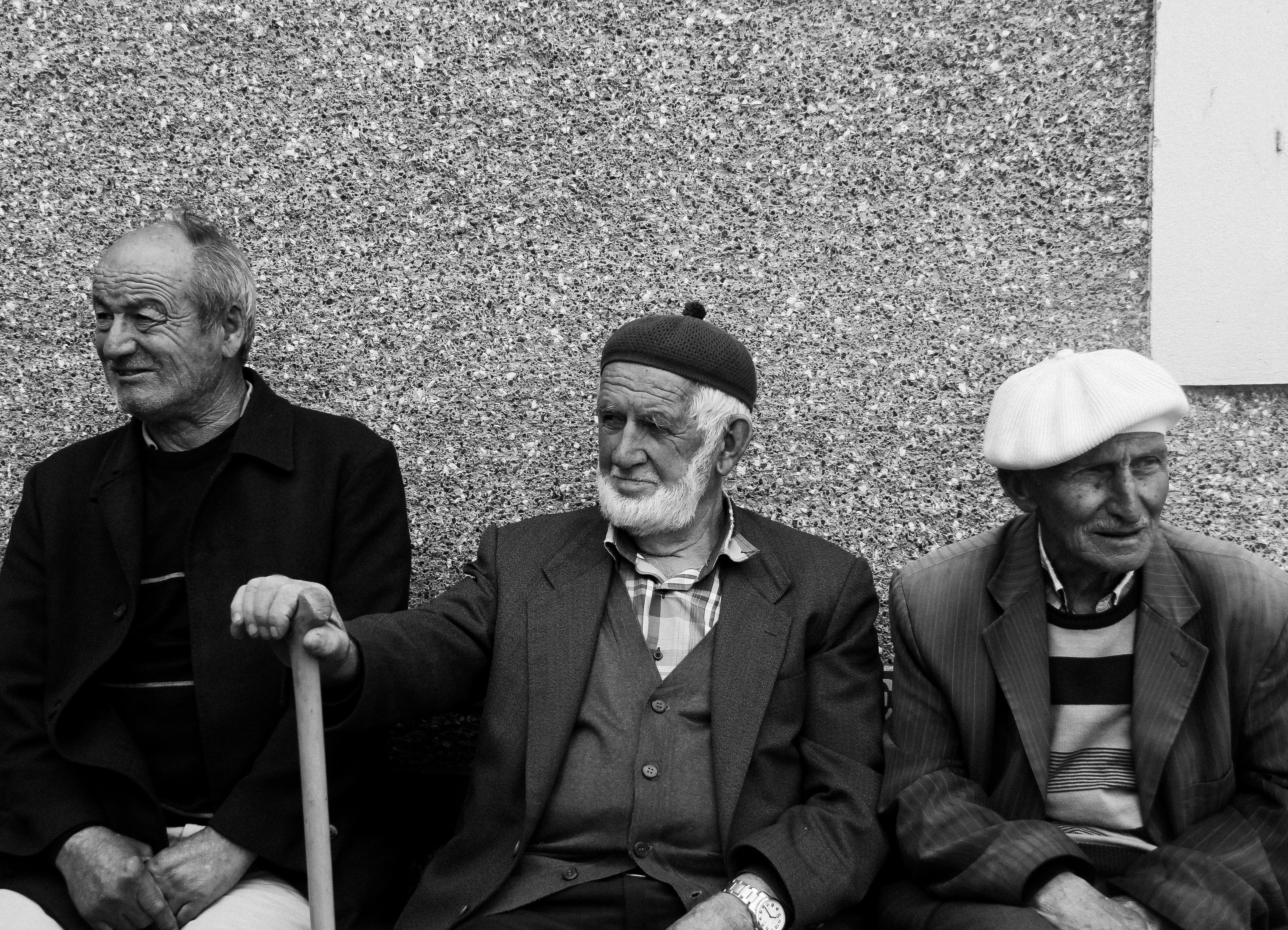 Three elderly men sitting and conversing in black and white, capturing timeless camaraderie.