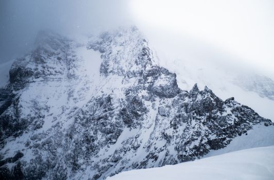 Stunning view of steep, snow-covered mountain peaks under cloudy winter skies.