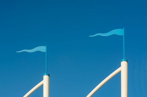 Free Two minimalist blue flags on poles against a clear blue sky, emphasizing simplicity and elegance. Stock Photo