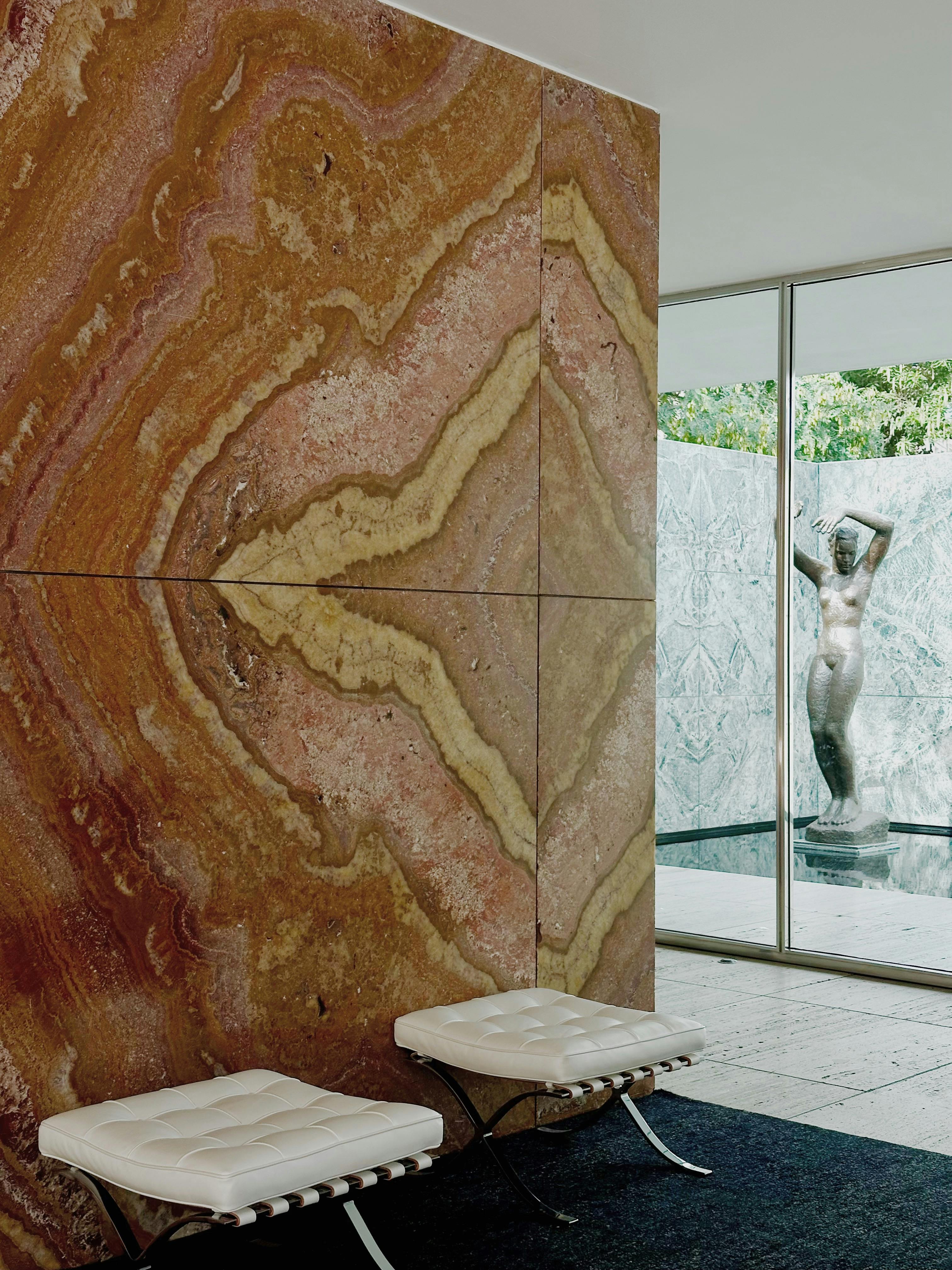 Elegant marble interior of Barcelona Pavilion with modern seating and sculpture view.