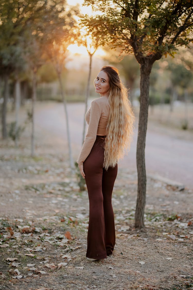 Woman With Curly Hair Posing Among Trees 