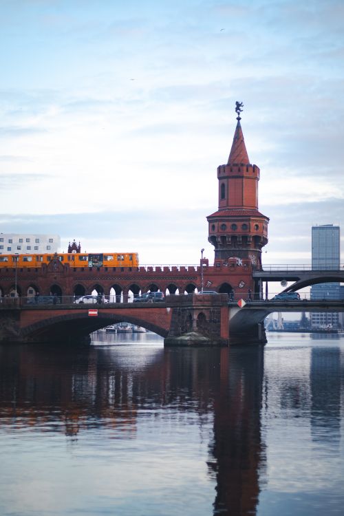 Free Scenic view of Berlin's Oberbaum Bridge with a train crossing at dusk, reflecting on the river. Stock Photo