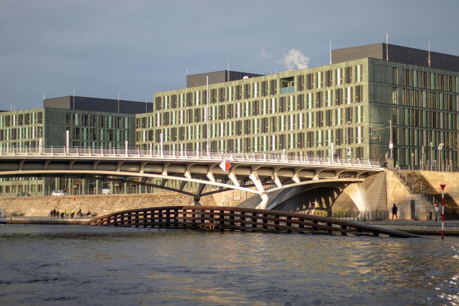 View of modern bridge and government buildings in Berlin, Germany along a river during the day.