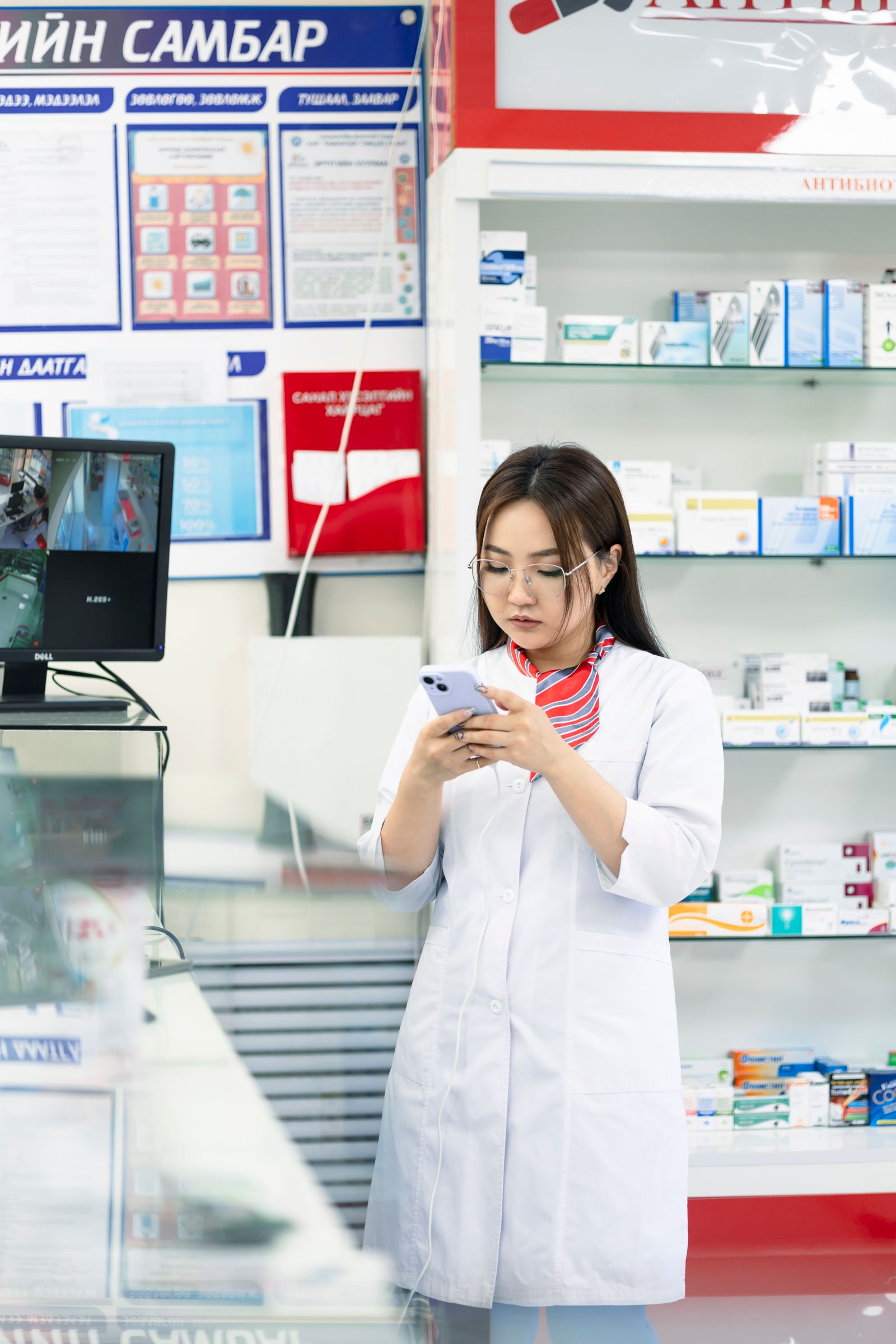 Pharmacist working in a pharmacy surrounded by medicine shelves