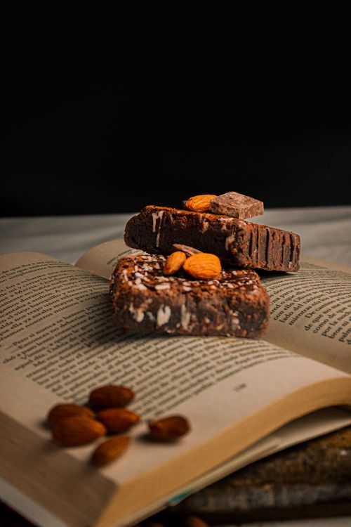 Free Tantalizing stack of chocolate brownies with almonds on an open book, perfect snack imagery. Stock Photo