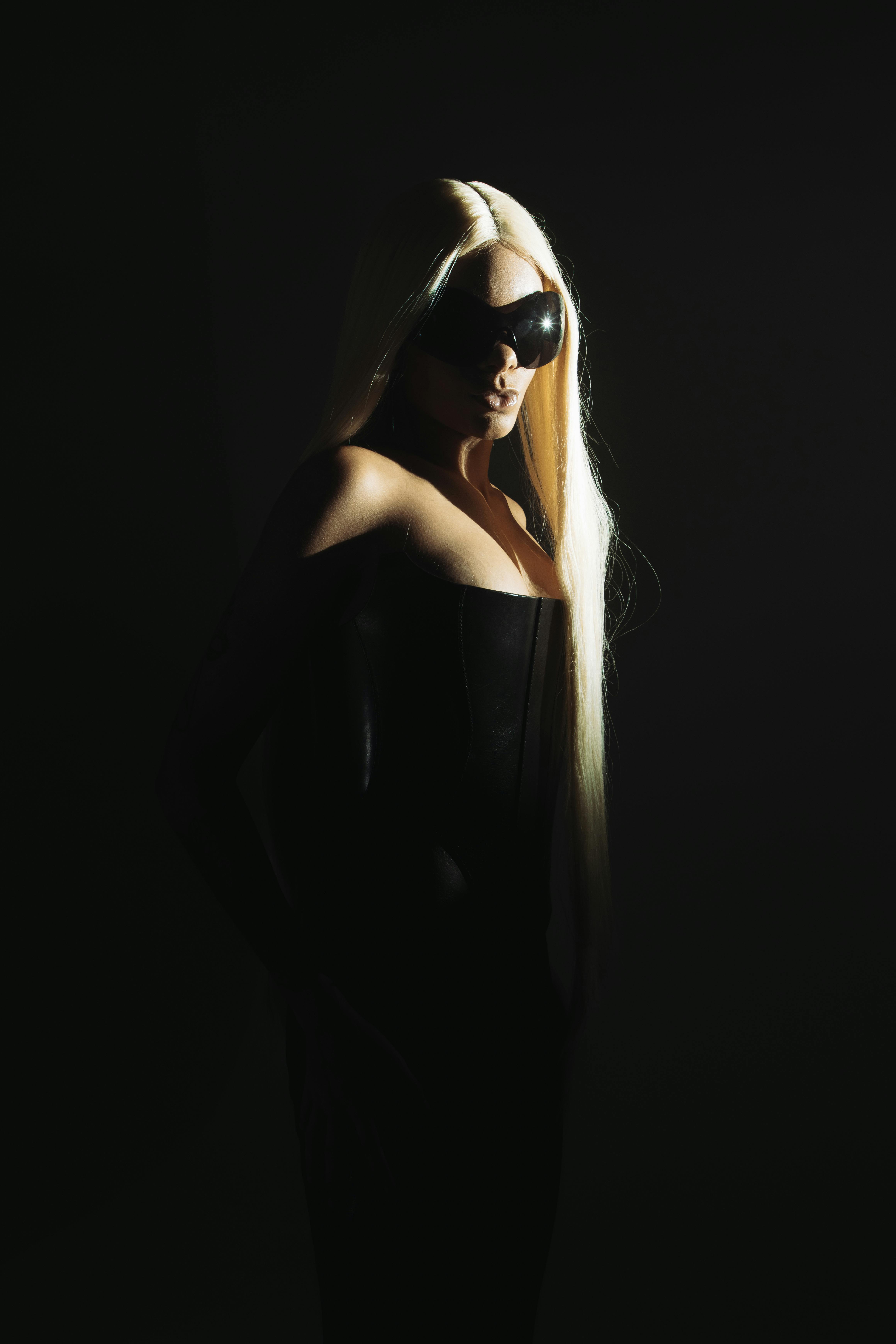 Mysterious woman in shadows wearing sunglasses and long blonde hair.