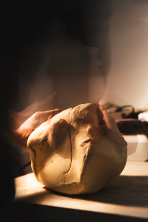 Free A baker's hands knead dough in soft sunlight, a warm kitchen scene. Stock Photo