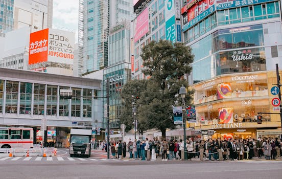 People waiting at the Shibuya crossing in Tokyo, showcasing vibrant urban life and architecture.