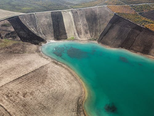 Aerial View of Plowed Farmlands over Turquoise Lake