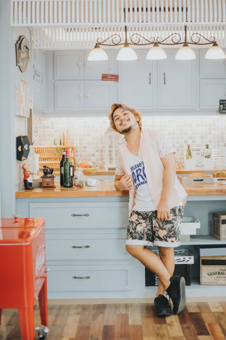 Smiling Man In Shirt And Shorts Standing In Kitchen