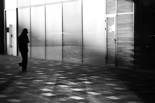 Silhouette of a Passerby on the Sidewalk in Front of Shop Windows