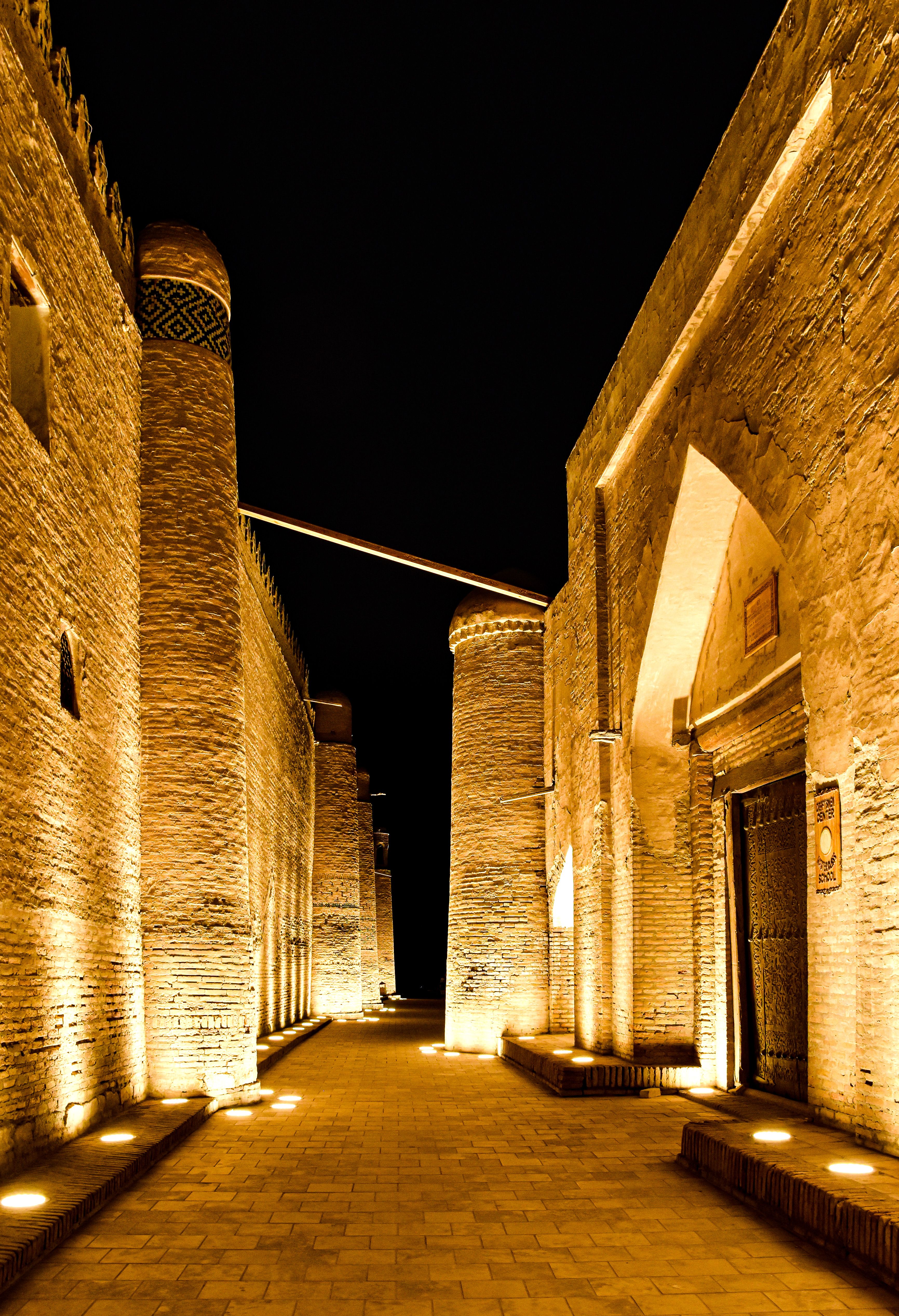 Illuminated ancient architecture in Khiva's old town at night, showcasing Islamic heritage.