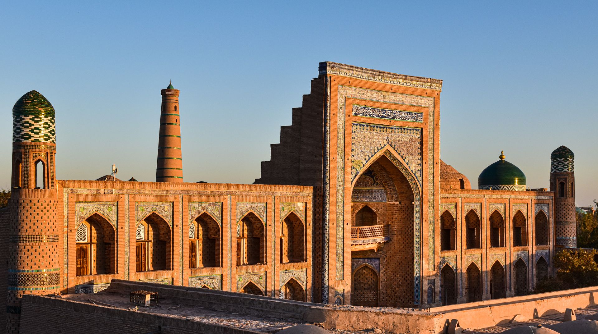 Stunning view of Mohammed Rakhim Khan Madrassah in Khiva with a clear sky at sunset.