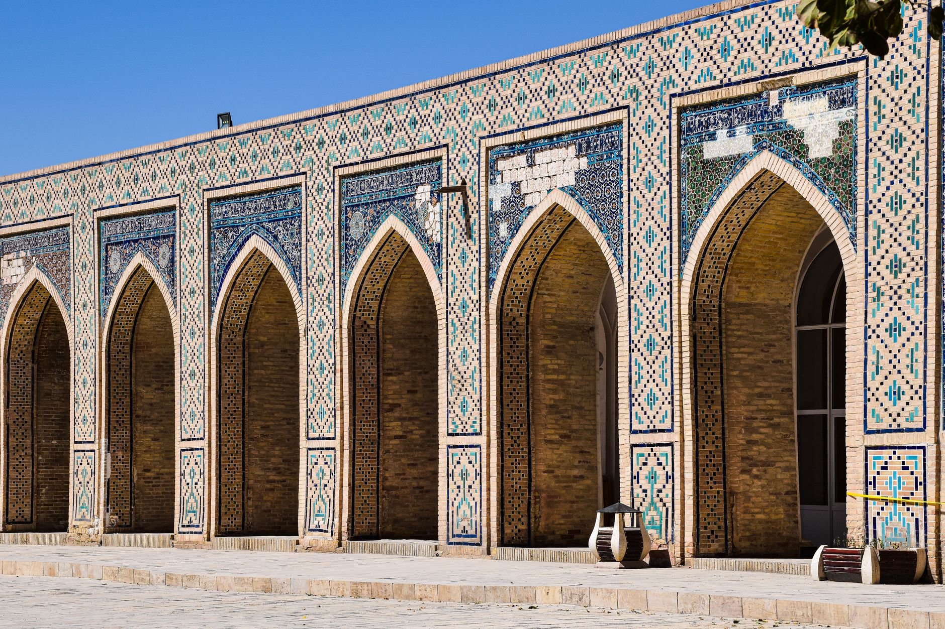Detailed view of the intricate arches and mosaic tiles of a historic mosque in Bukhara, Uzbekistan.