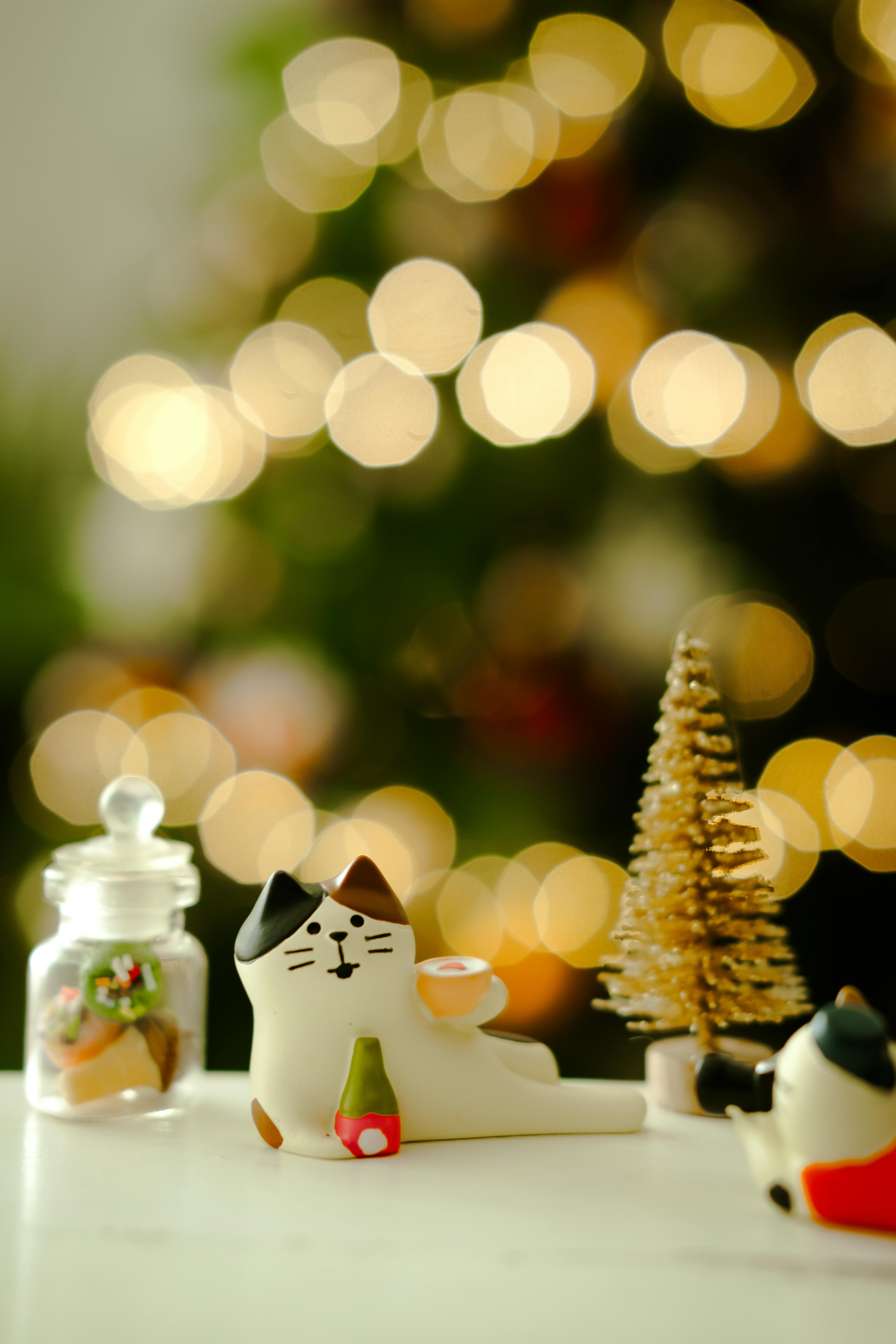 Cute cat figurines with Christmas tree and festive lights bokeh in Hồ Chí Minh, Vietnam.