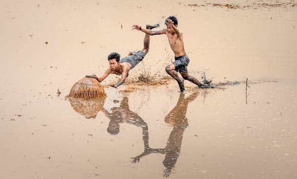 Boys play joyfully in a muddy wetland, embracing the fun of rural life.
