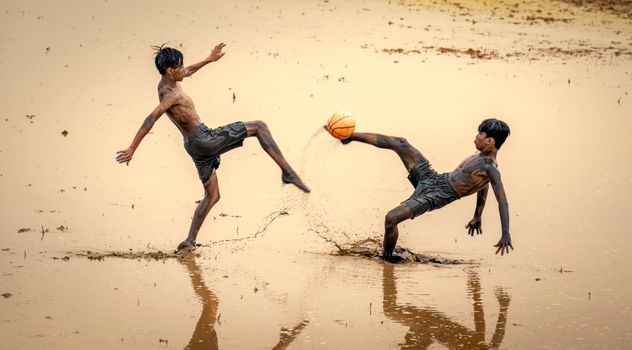 Energetic teenagers playing soccer in a muddy field, showcasing rural fun and passion.