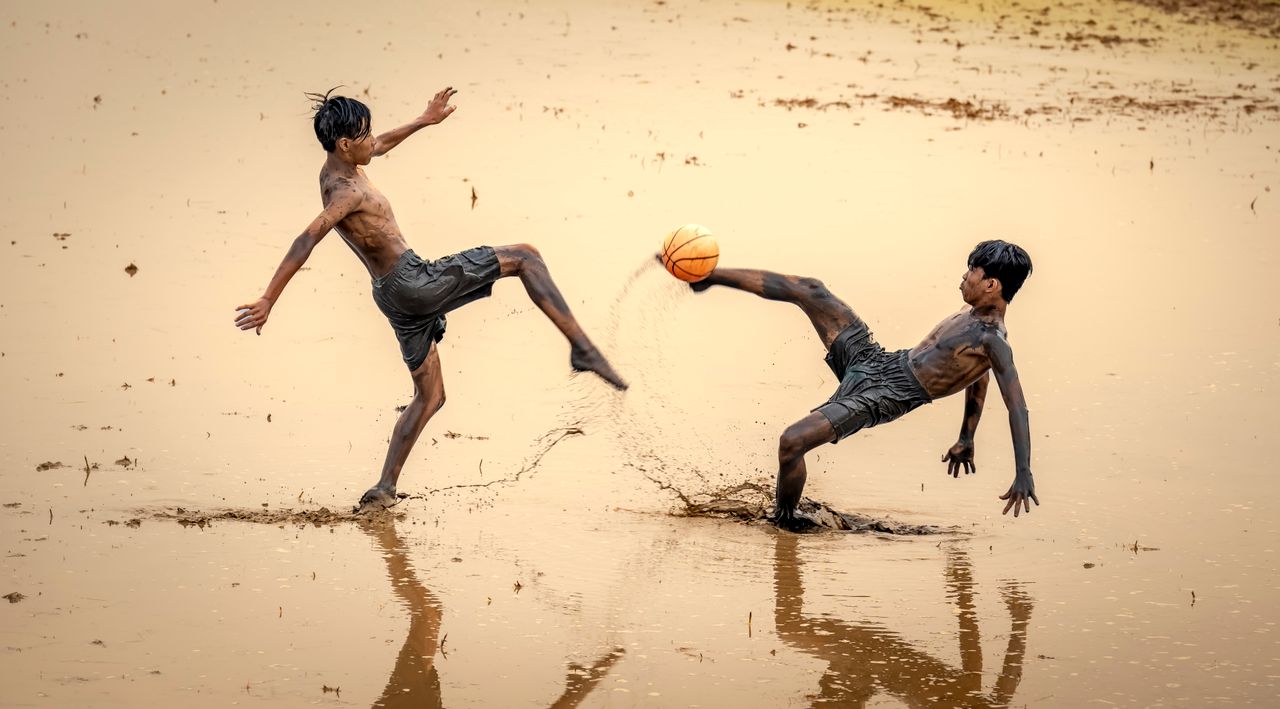 energetic teenagers playing soccer in a muddy field showcasing rural f