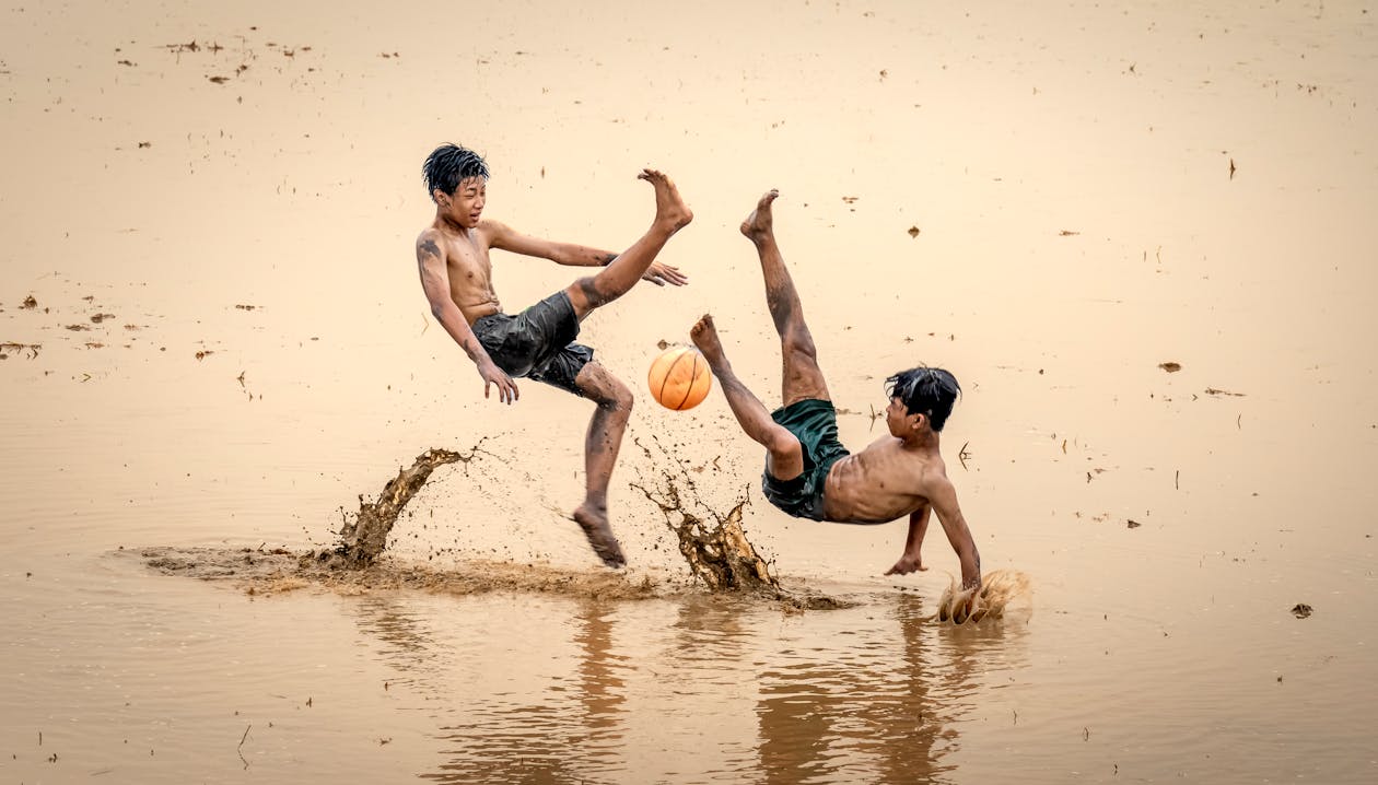 Boys Playing Soccer in Muddy Water