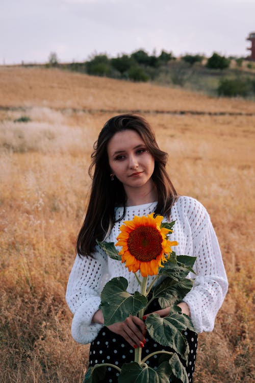 Woman Holding a Sunflower in a Field 