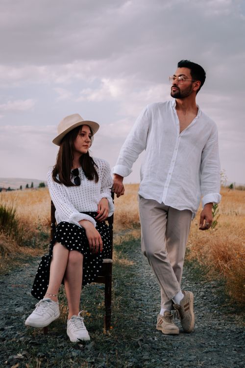 Free A couple poses stylishly on a dirt road amid a golden autumn field. Stock Photo