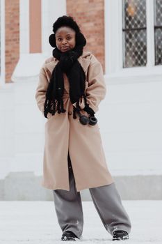 Stylish woman in winter coat and scarf standing outdoors in snowy Jönköping, Sweden.