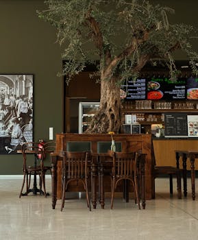 Warm restaurant interior in Berlin, featuring unique olive tree decor and classic furniture.