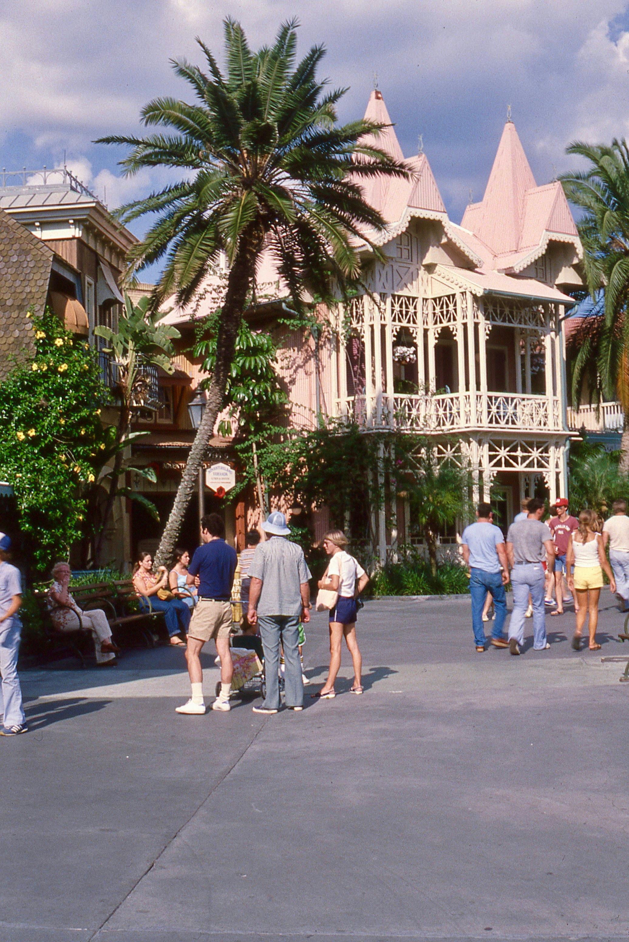 Orlando resort scene with tourists and Victorian-style architecture amid palm trees.